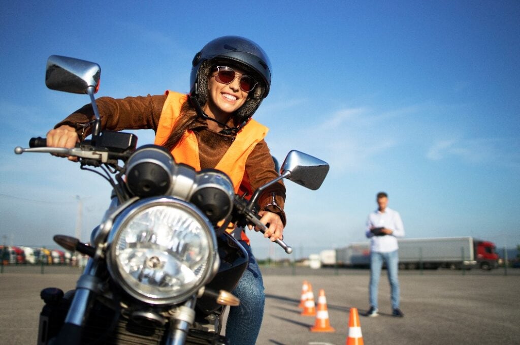 Weibliche Studentin mit Helm nimmt Motorradunterricht und übt